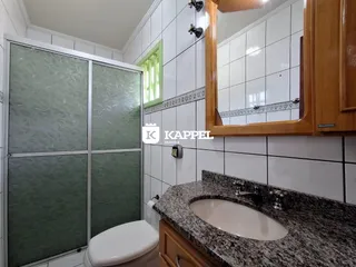 Banheiro com bancada de granito e revestimento de azulejos brancos.