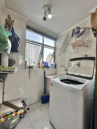 Interior de uma área de serviço com máquina de lavar e janela de vista para a cidade.