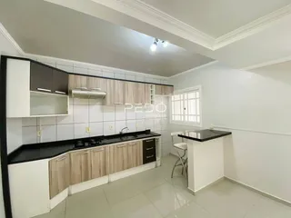 Cozinha com armários e bancadas escuras em um imóvel no Brasil.
