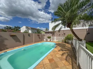 Piscina externa com área de lazer e muro no quintal.