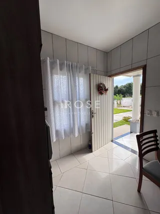 Vista interna de um ambiente com piso de cerâmica clara e cortinas brancas.