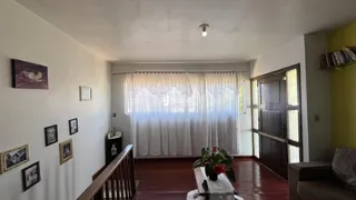 Sala de estar com piso de madeira e cortinas brancas.