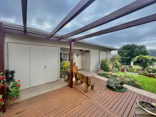 Vista da fachada de uma residência com deck de madeira e jardim em Lajeado.