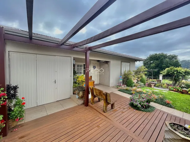 Vista da fachada de uma residência com deck de madeira e jardim em Lajeado.