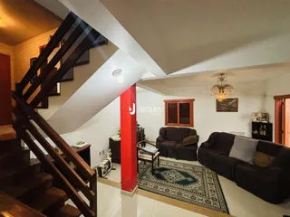 Vista interna de uma sala com escadaria e dois sofás.