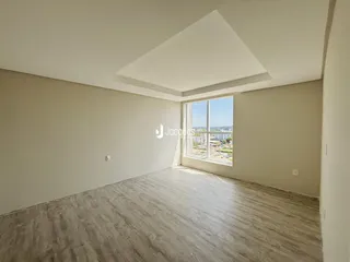 Vista interna de um cômodo com teto inclinado e grande janela.
