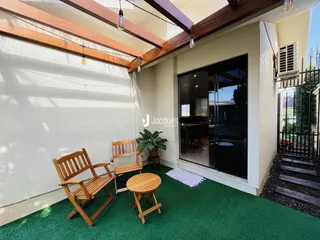 Área externa com móveis de madeira e piso verde.
