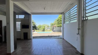Área coberta com piso de cerâmica que dá acesso a uma piscina e jardim.