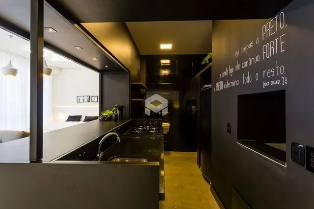 Vista da cozinha moderna com armários escuros e bancadas de aço inoxidável.