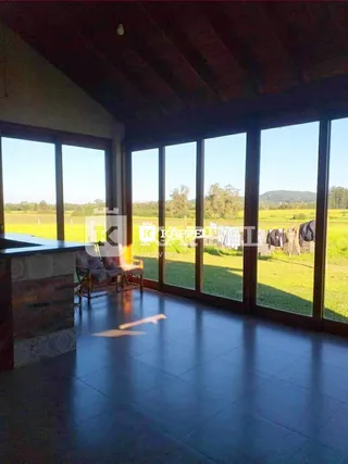 Sala de estar com grandes janelas que oferecem vista para um campo aberto.