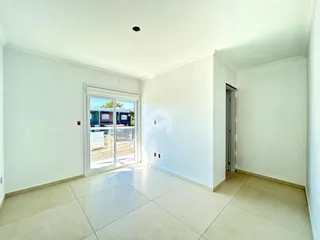 Interior de uma sala com piso de cerâmica e porta de vidro abrindo para o exterior.