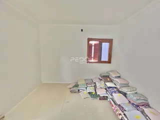 Quarto vazio com paredes brancas e uma janela de madeira.