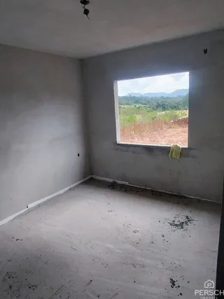 Foto de um cômodo vazio com paredes brancas e piso de concreto exposto.