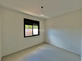 Sala de estar com paredes brancas e piso claro.