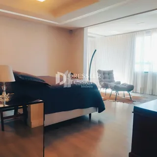 Quarto com cama grande e janelas iluminadas.