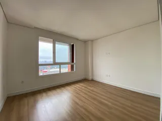 Sala de estar clara com piso de madeira e grande janela com vista para a paisagem.