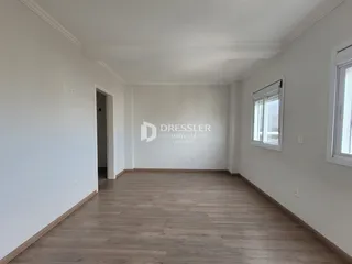 Uma sala de estar com piso de madeira clara e paredes brancas.