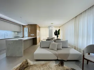 Sala de estar moderna com cozinha integrada e grandes janelas.