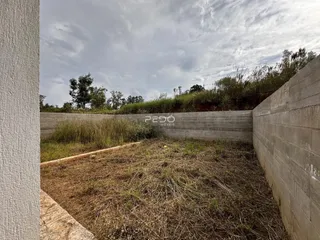 Vista externa de um terreno cercado por muros de concreto e vegetação.