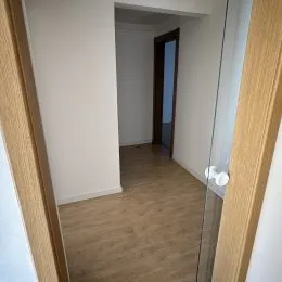 Foto de um corredor interno com paredes brancas e piso de madeira.