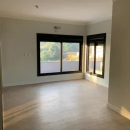 Foto de um ambiente interno com piso de madeira e janela grande.