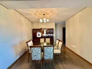 Ambiente de jantar com mesa de madeira e cadeiras decoradas.
