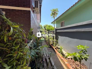 A foto mostra a fachada de uma residência com vegetação densa no jardim.
