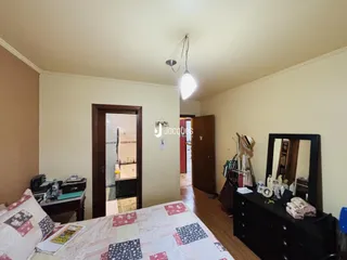 Quarto com piso de madeira e porta de entrada para o banheiro.