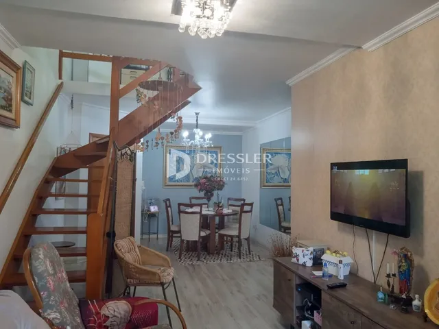 Interior de uma sala de jantar com escadaria de madeira em uma residência.
