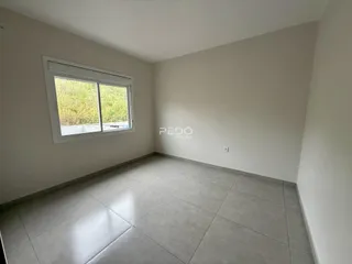 A sala possui piso de cerâmica e uma grande janela com vista para a vegetação.