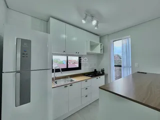 Cozinha moderna com armários brancos e bancada de madeira.