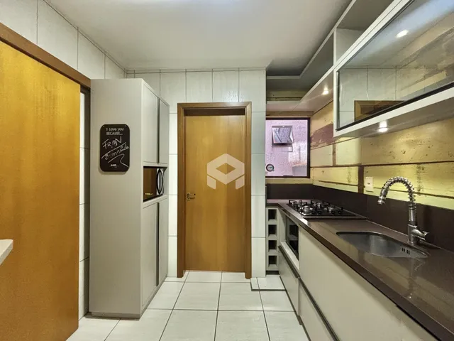 Interior de uma cozinha com armários e portas de madeira clara.