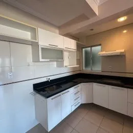 Foto de uma cozinha com armários brancos e bancada escura.