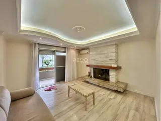 Sala de estar com piso de madeira clara e lareira em um imóvel no Brasil.