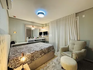 Quarto com cama e poltrona em ambiente claro.