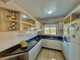 Foto de uma cozinha moderna com armários brancos e bancadas escuras.