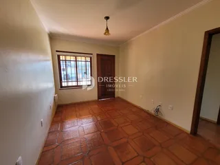 Sala de estar com piso de cerâmica e porta de madeira em um imóvel no Brasil.