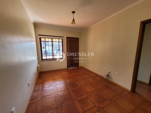Sala de estar com piso de cerâmica e porta de madeira em um imóvel no Brasil.