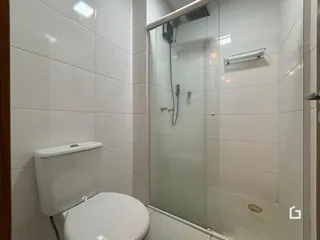 Foto de um banheiro com revestimento de azulejos brancos e box de vidro.