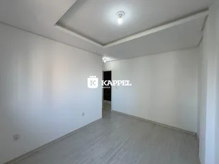 Hall de entrada com paredes brancas e piso claro.