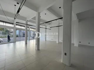 Interior de uma sala ampla com pé direito alto e colunas brancas.