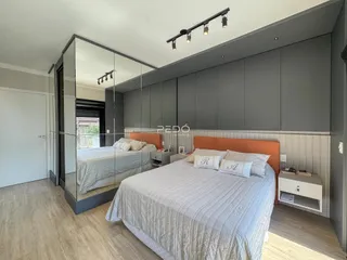 Quarto moderno com cama e espelho refletindo o ambiente.
