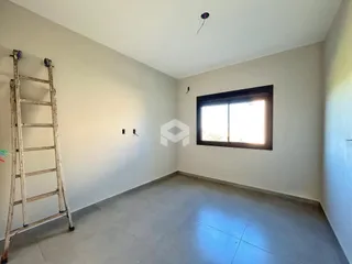 Sala de estar vazia com paredes brancas e piso de concreto.