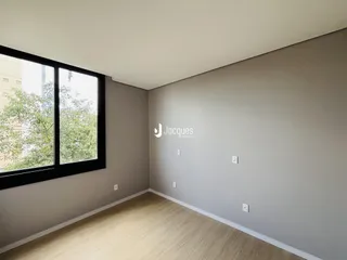 Ambiente interno de uma sala com piso de madeira e grande janela.