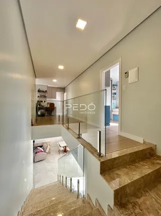 Hall com guarda-corpo de vidro e degraus de mármore.