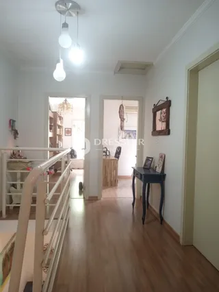 Hall de entrada com piso de madeira e corrimão de escada branca.