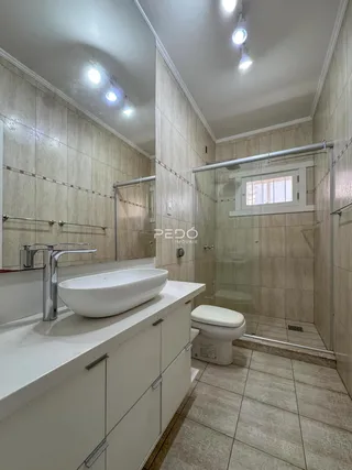 Foto de um banheiro com box de vidro e bancada branca.