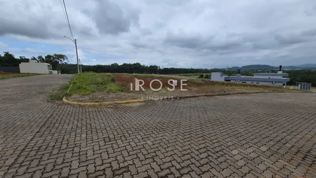 Vista externa de uma propriedade com área pavimentada e vegetação ao fundo.