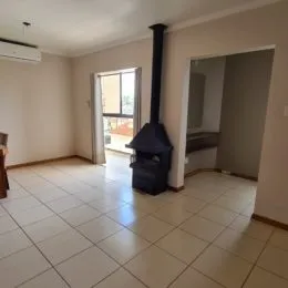 Ambiente interno com piso de cerâmica e coluna escura em uma sala.