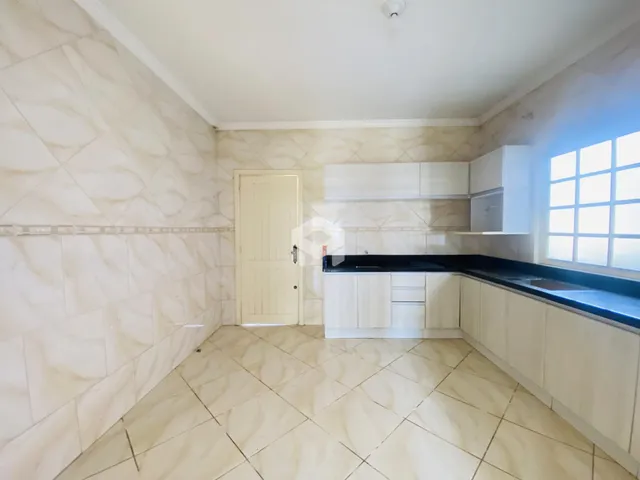 Foto de uma cozinha com revestimento de cerâmica clara e armários brancos.